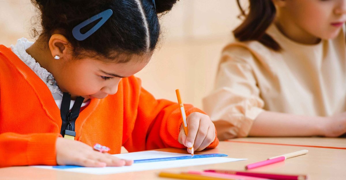Enfant concentrée en train d'écrire en classe